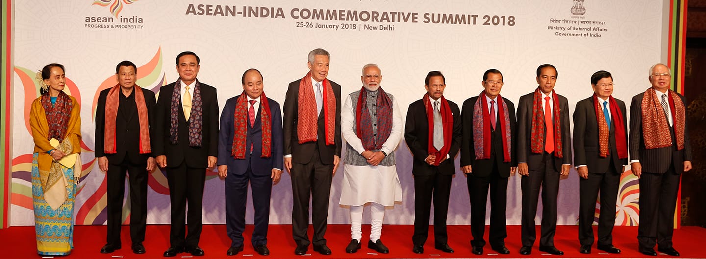 Group of dignitaries in suits, some with red scarves, at ASEAN-India summit 2018. Modi is at center.